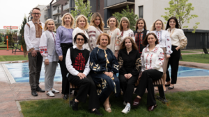 Group of people wearing traditional embroidered clothing posing together in an outdoor courtyard by a pool.